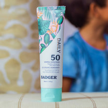 Load image into Gallery viewer, Badger sunscreen tube with tropical leaf design on a blurred background