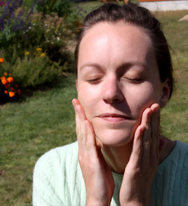 Badger Brenna rubbing anioxidant rich oil onto her face outside in the sun